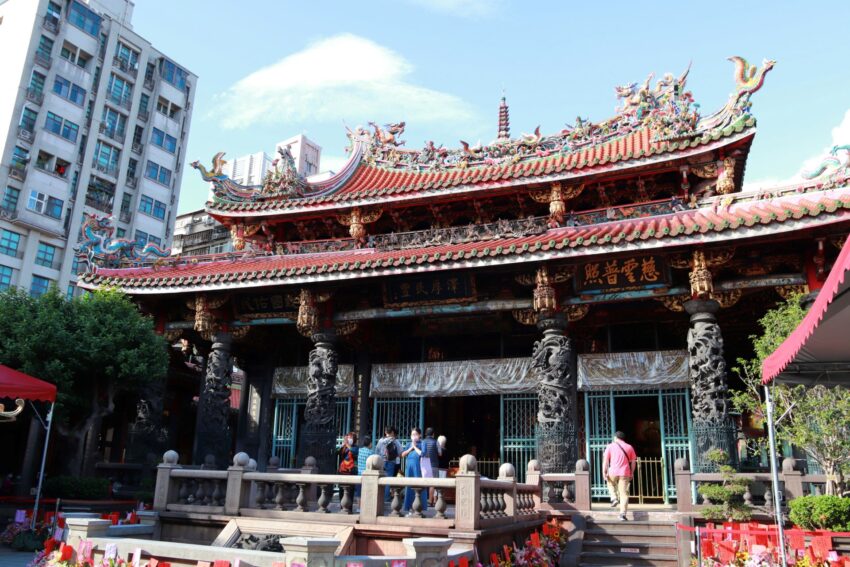 龍山寺の朱塗りの門と参拝者の様子