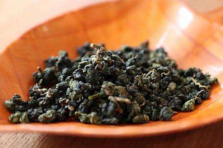 梨山高冷茶の茶葉と水色。薄い緑がかった金黄色が特徴的。