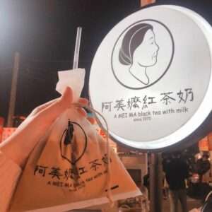 阿美嬤紅茶牛奶。白いシンプルな看板が夜市の中で目を引くドリンク屋台