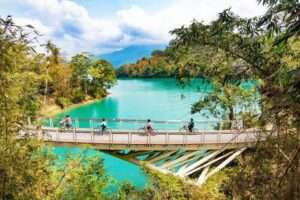 日月潭の環湖サイクリングコース沿いの秋の景色。旅行者が永結橋を自転車で走り抜ける