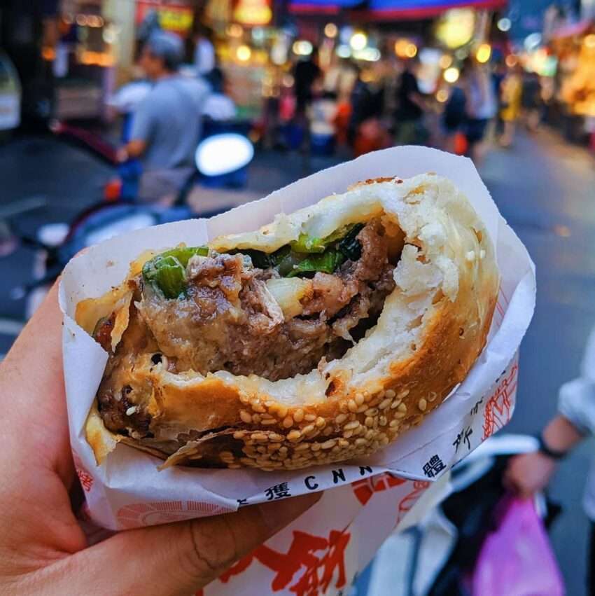 福州世祖胡椒餅が焼き上がった様子。表面に金色のごまがついており、炭火の窯の壁に複数の餅が貼り付けられている