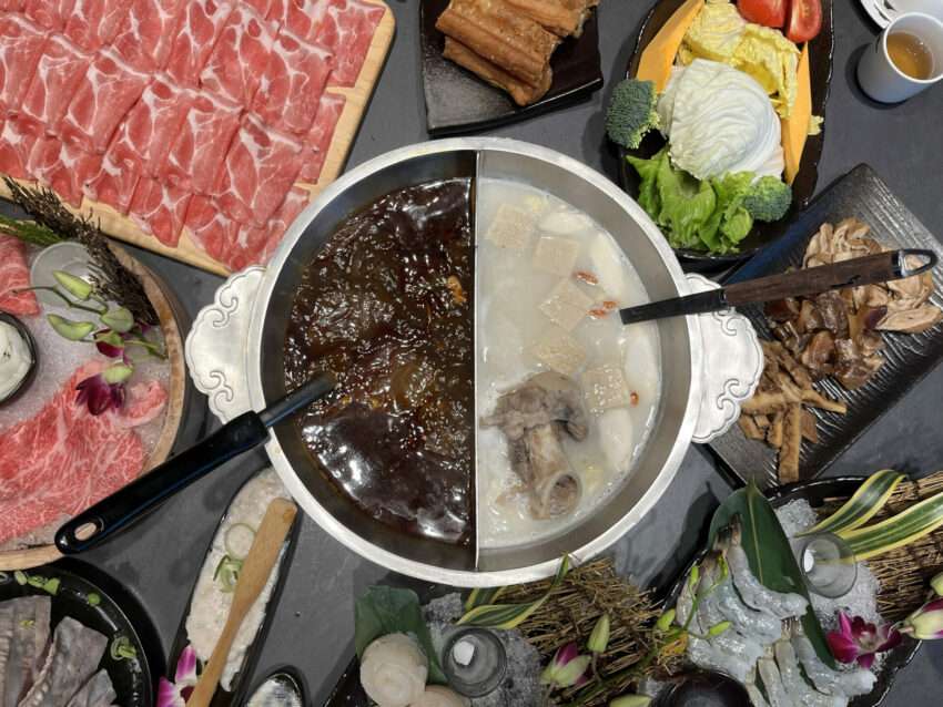 岩漿火鍋の麻辣スープ。鮮やかな赤色のスープが沸騰し、豊富な食材が入っている