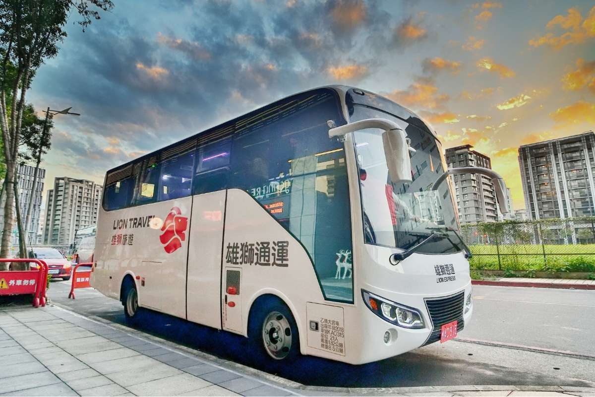 阿里山の郵輪式バスが山道の路肩に停車し、旅行者が乗り込もうとしています