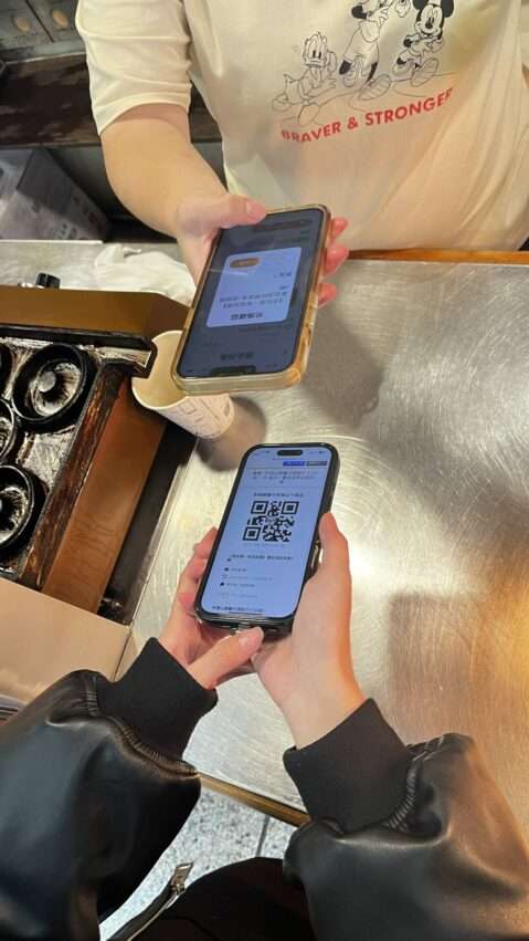 旅行者がQRコードを奮起湖の店舗スタッフに提示して特典を受け取っている