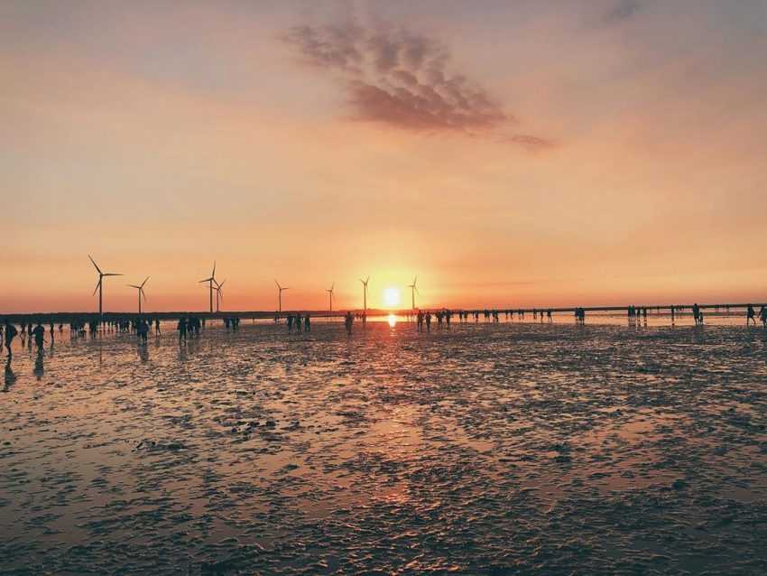 干潮後の泥干潟の水面に夕日が映り込んでいる