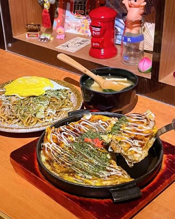 水沐食堂のお好み焼き。表面にソースとマヨネーズが塗られ、かつお節がのっている