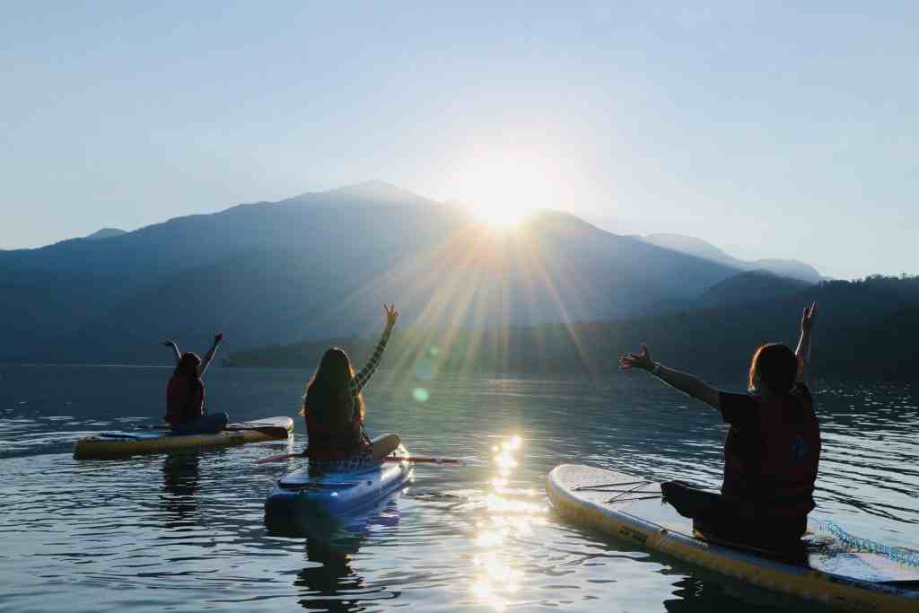 日月潭の湖面でSUP（スタンドアップパドルボード）を楽しむ旅行者。穏やかな湖面でパドリングを体験