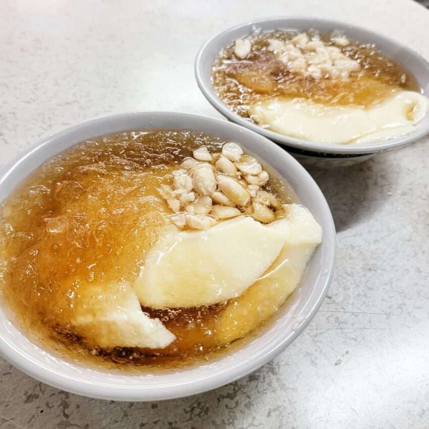 龍潭豆花が器に盛られ、ピーナッツ・タピオカ・小豆などのトッピングが添えられている