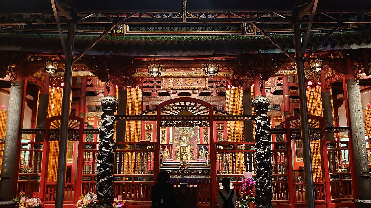 龍山寺の本殿内部と参拝者、極彩色の装飾が施された天井