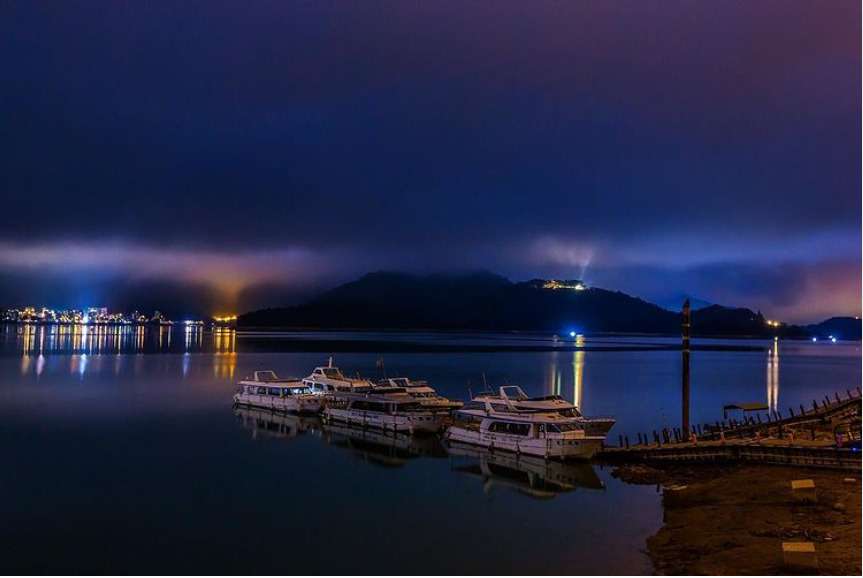 日月潭の桟橋の夜景。湖の光と遠くの山が映り合っている