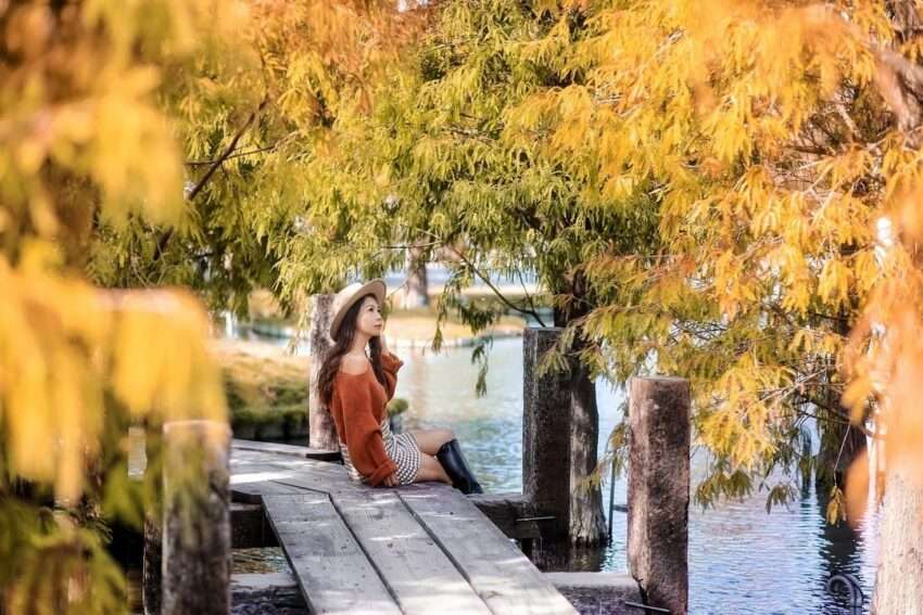 屋外で葉っぱを拾う自然な写真ポーズの女性