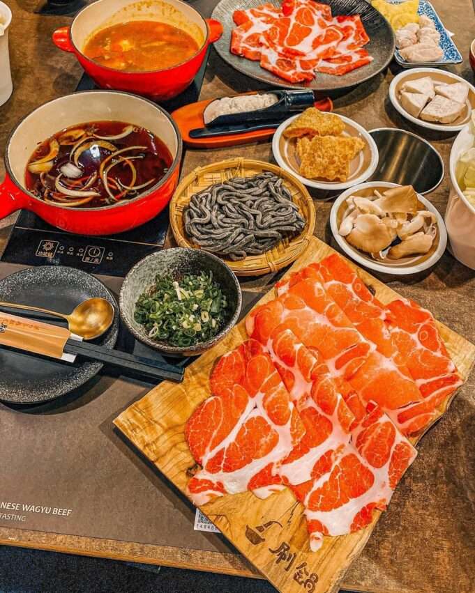 刷鍋 台南総店のテーブルに並ぶ新鮮な肉と野菜のプレート