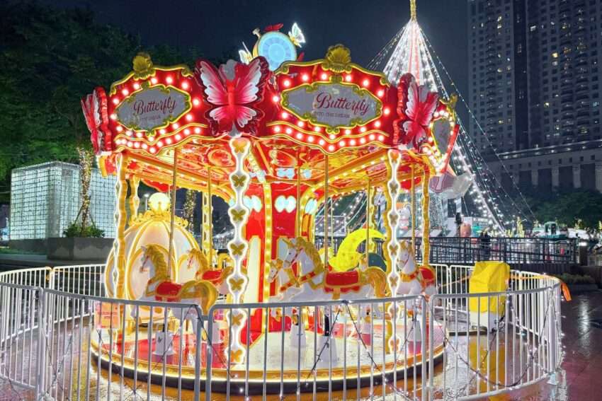 クリスマスシティ市民広場のメリーゴーランドがイルミネーションに包まれた夜間の様子